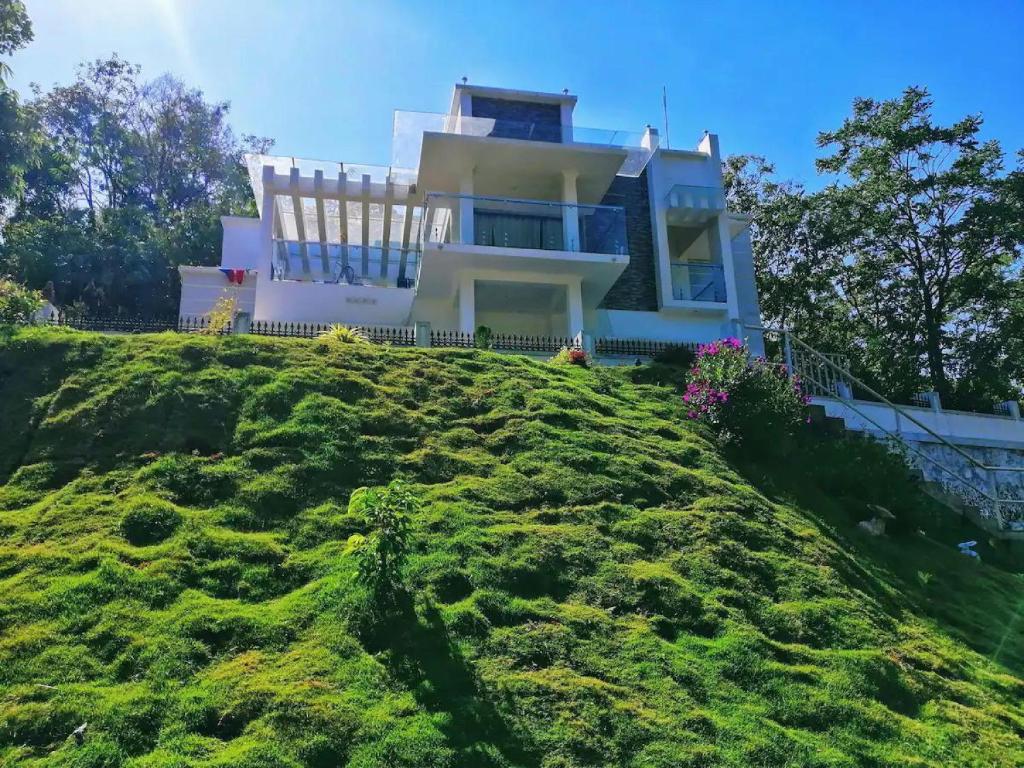 uma casa no topo de uma colina relvada em The White Bloom 3BHK em Munnar