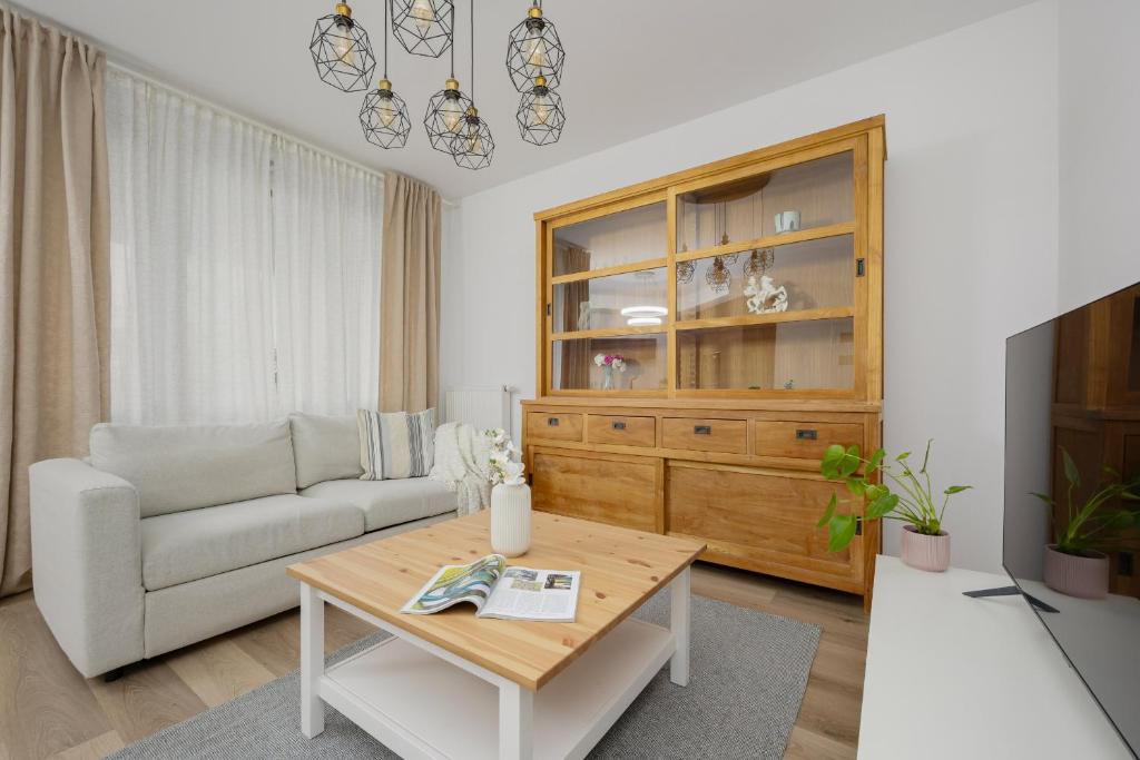 ein Wohnzimmer mit einem Sofa und einem Tisch in der Unterkunft Złoty Potok Modern Family Apartment with Balconies & Parking Warsaw by Renters in Warschau