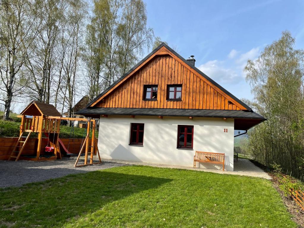 una casa con techo naranja y parque infantil en Chata GOLDENBACH en Malá Morava