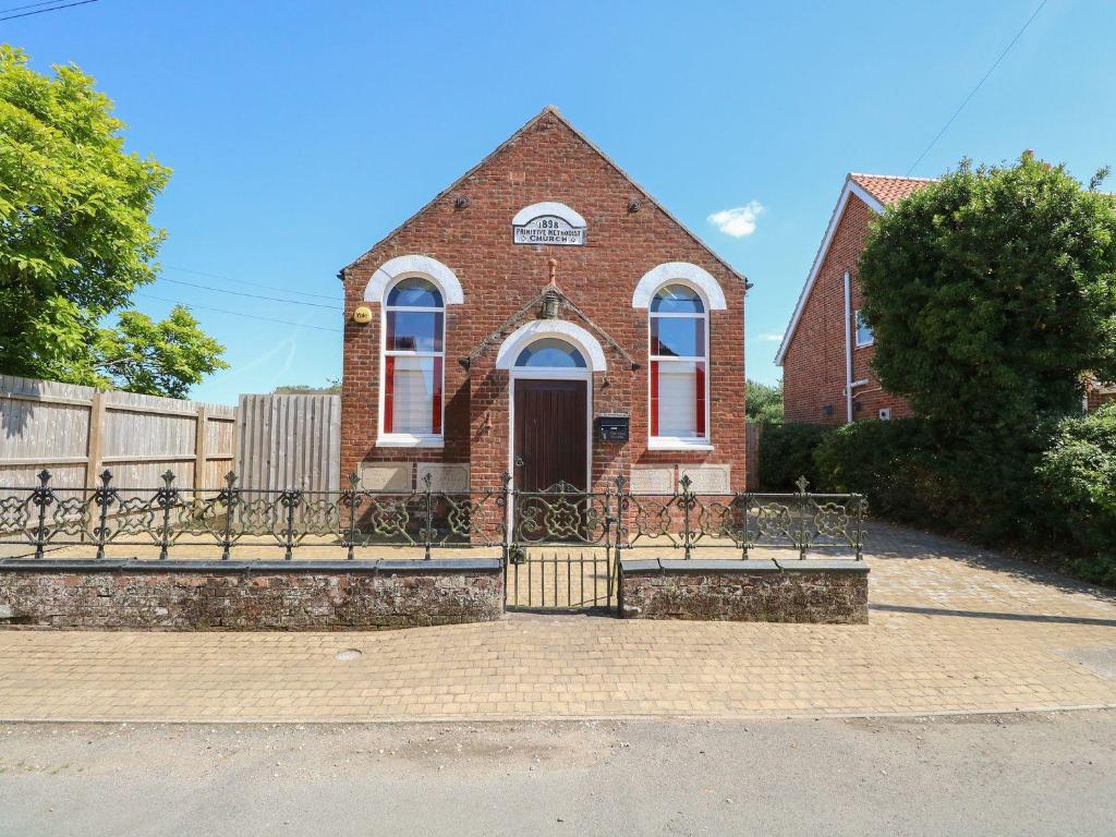 a brick house with a gate in front of it at The Old Chapel in Bawdeswell