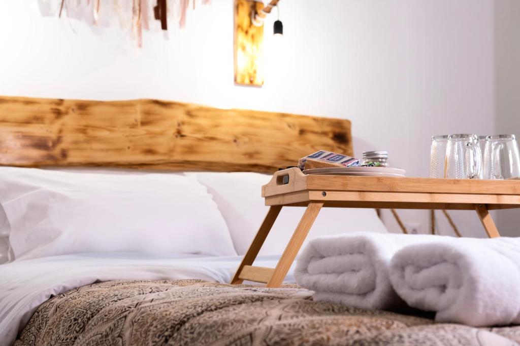 a bed with a wooden table next to a table with towels at Onar Syros - Rustic Rooms in Ermoupoli