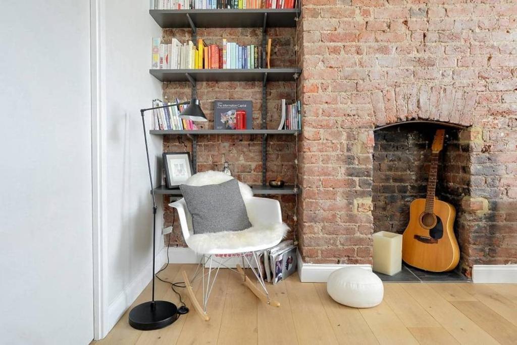 een kamer met een bakstenen muur met een stoel en een gitaar bij GuestReady - Beautiful flat near Kings Cross in Londen