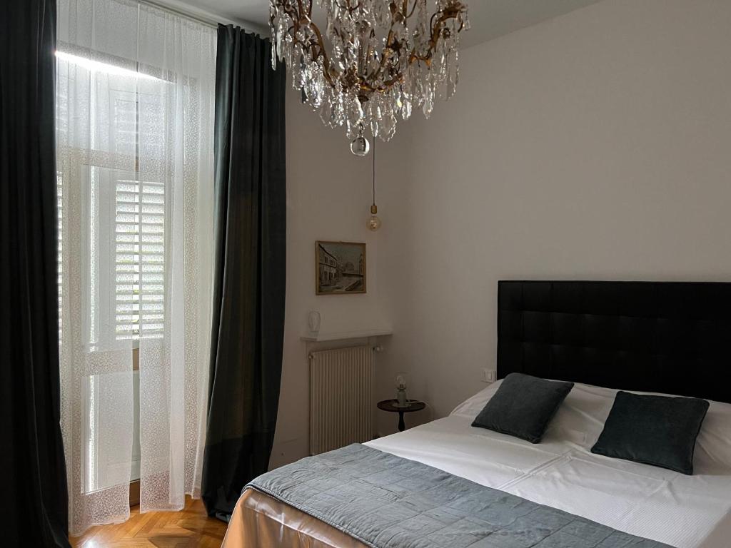 een slaapkamer met een bed en een kroonluchter bij Garden View boutique apartments in Gorizia