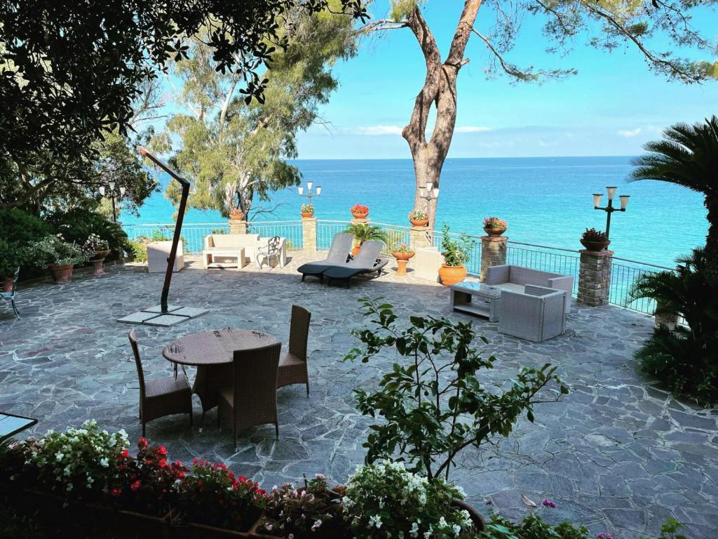 un patio con mesa, sillas y el océano en DONNA STEFANIA SEA FRONT, en Santa Maria di Castellabate