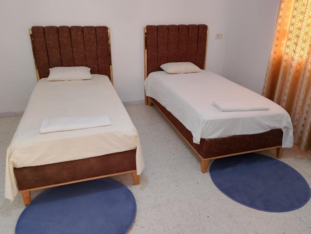 two beds in a room with two blue mats at Bella casa in Tataouine