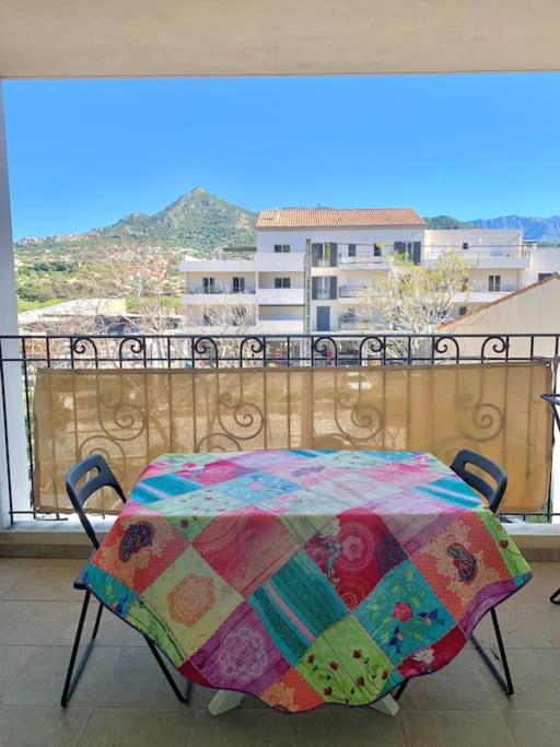 une table avec une couverture colorée sur un balcon dans l'établissement Appartement centre ville - 4p, à LʼÎle-Rousse