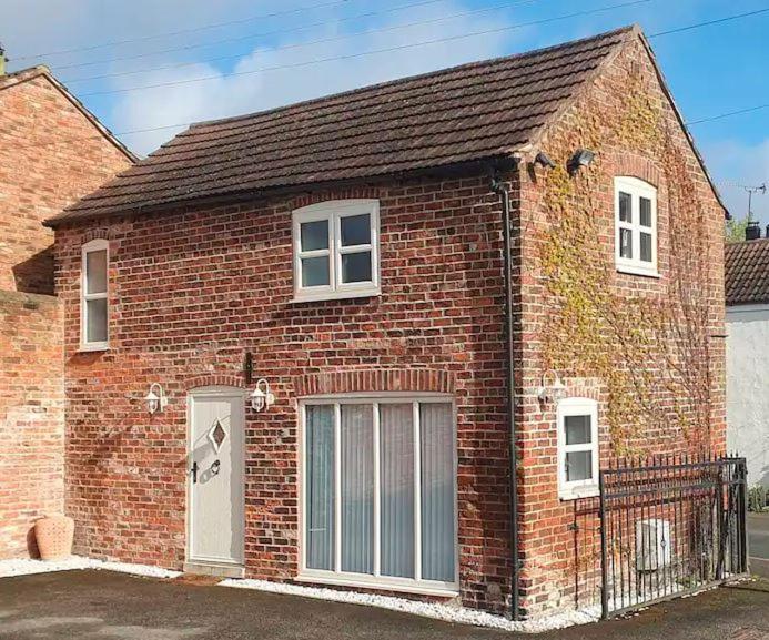 - un bâtiment en briques rouges avec une porte blanche dans l'établissement Country Cottage Barn Conversion, à Pollington