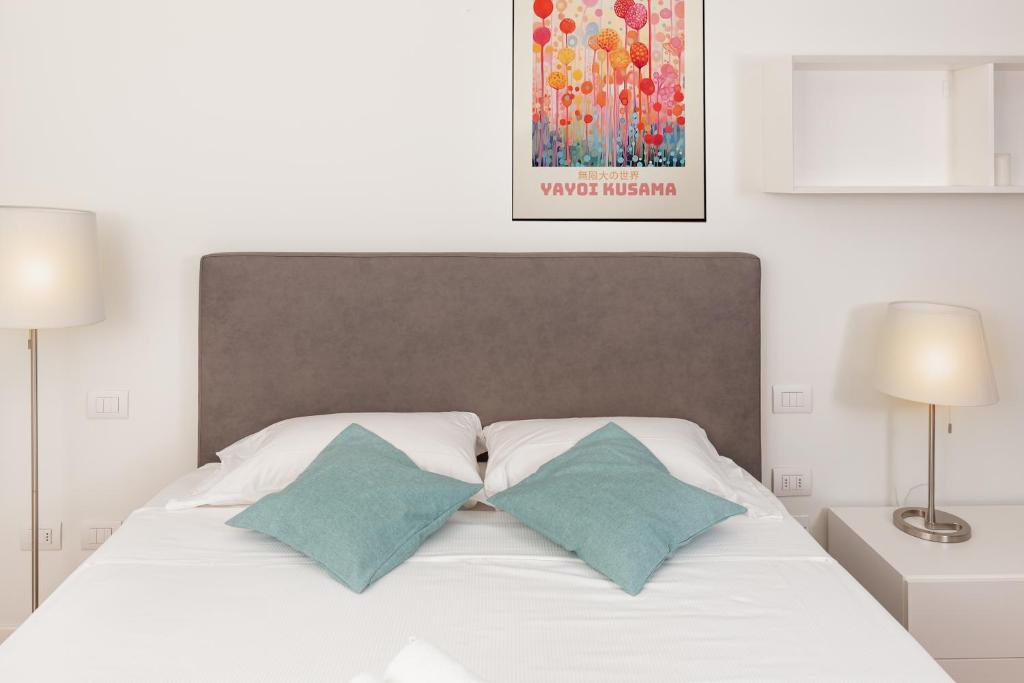 - une chambre avec un lit blanc et 2 oreillers bleus dans l'établissement Gym and Pool Exclusive Apartment, à Milan