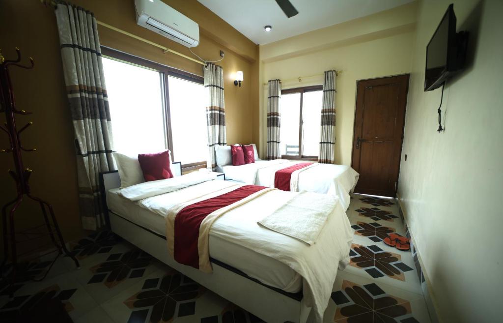 two beds in a room with a window at Hotel Flycatcher Chitwan in Sauraha
