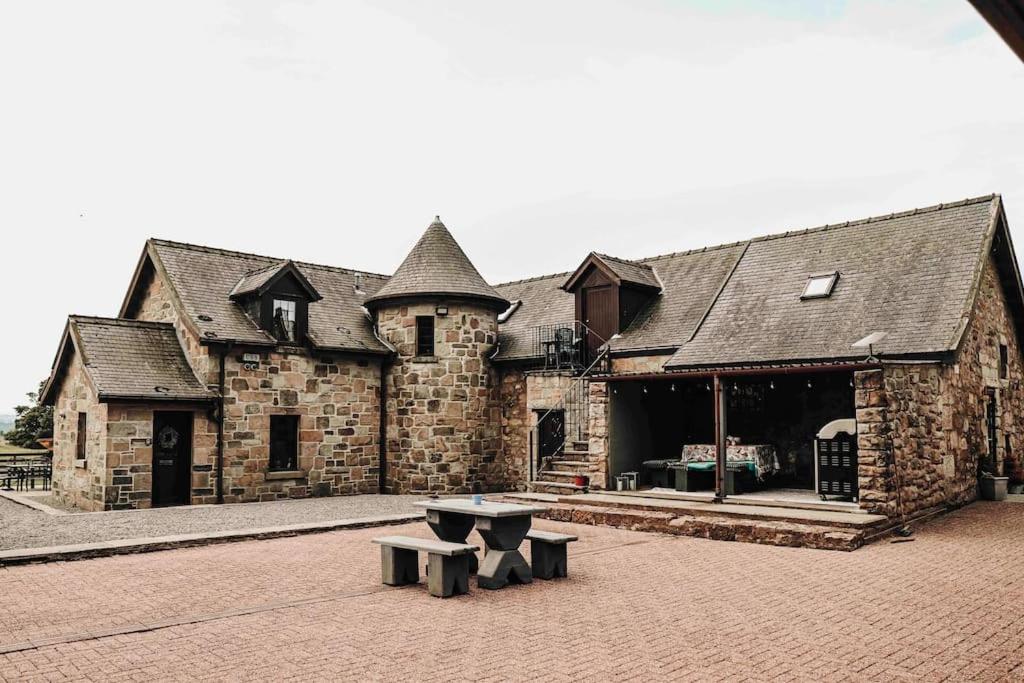 - un grand bâtiment en pierre avec des bancs devant dans l'établissement Barraston Farm Country Retreat, à Balmore