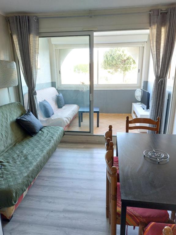 ein Wohnzimmer mit einem Sofa und einem Tisch in der Unterkunft Résidence les Floralies 2 - Avenue de Camargue in Le Grau-du-Roi
