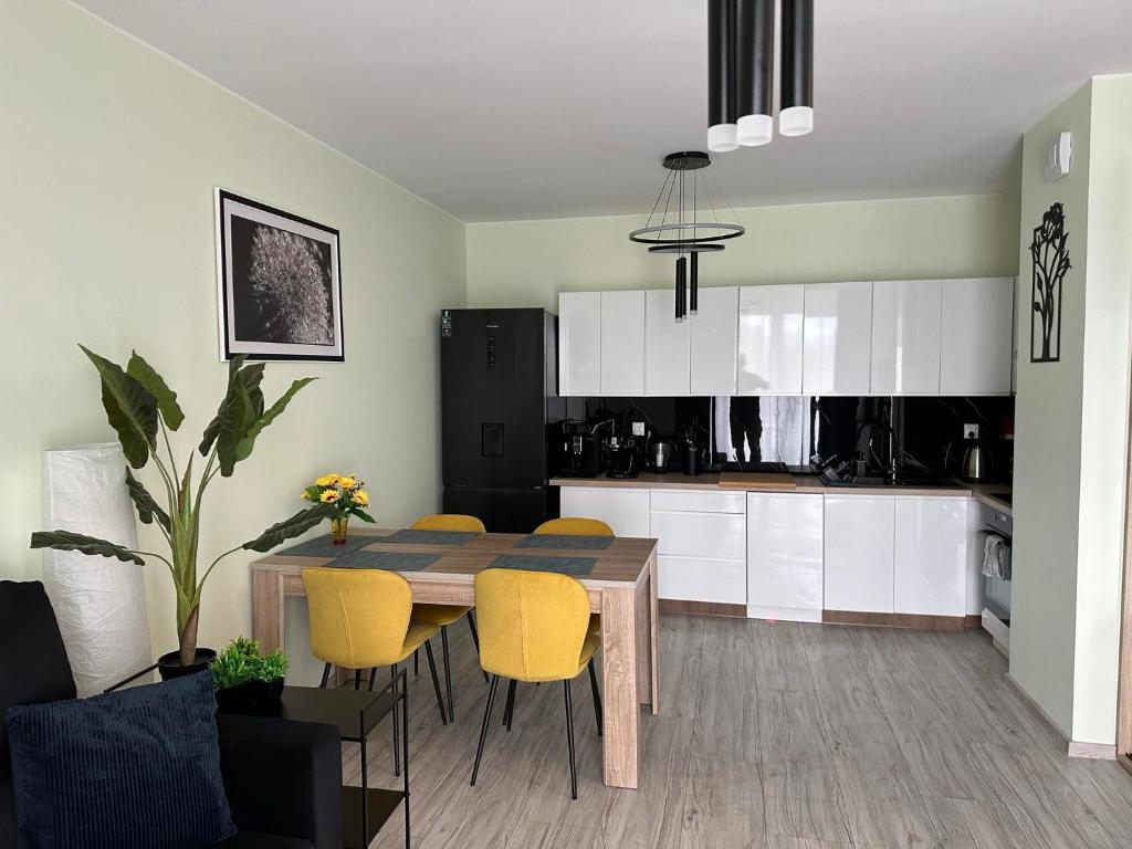 a kitchen and dining room with a table and yellow chairs at Apartament NATURA z widokiem na jezioro in Iława