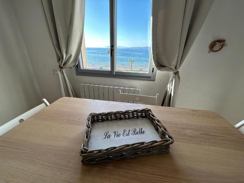 un panier en osier posé sur une table avec une fenêtre dans l'établissement Studio les pieds dans l eau au Brusc 4 personnes, à Six-Fours-les-Plages