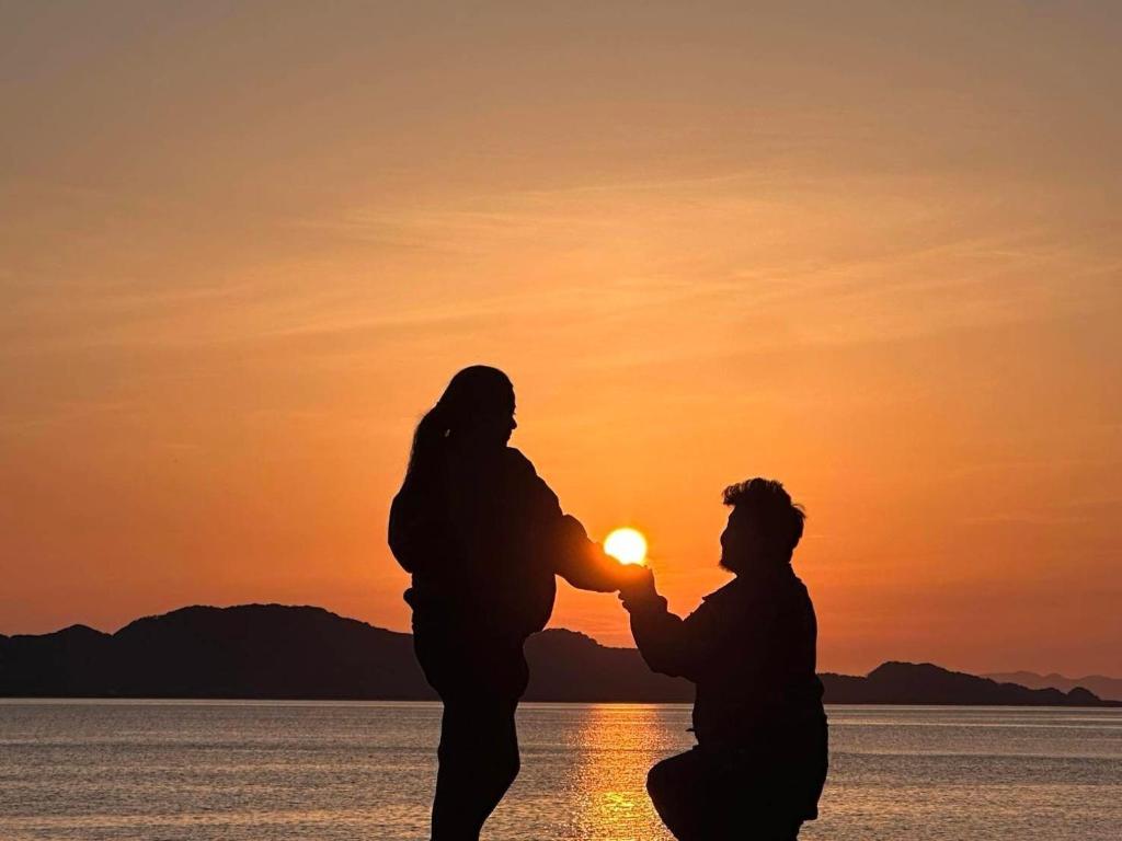 um homem e uma mulher de pé na praia ao pôr-do-sol em ImagineWestOcean - Vacation STAY 15909 em Suo Oshima