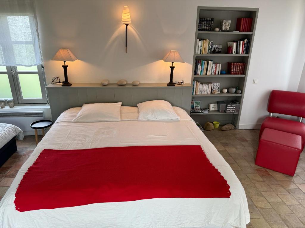 a bedroom with a large bed and a red chair at Ma Chambre d'Amis in Saint-Clément-des-Baleines