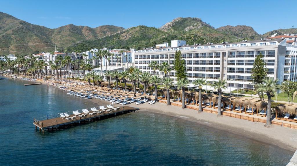 a resort on a beach with a pier and chairs at Prime Beach Hotel Ex Ideal Prime Beach in Marmaris