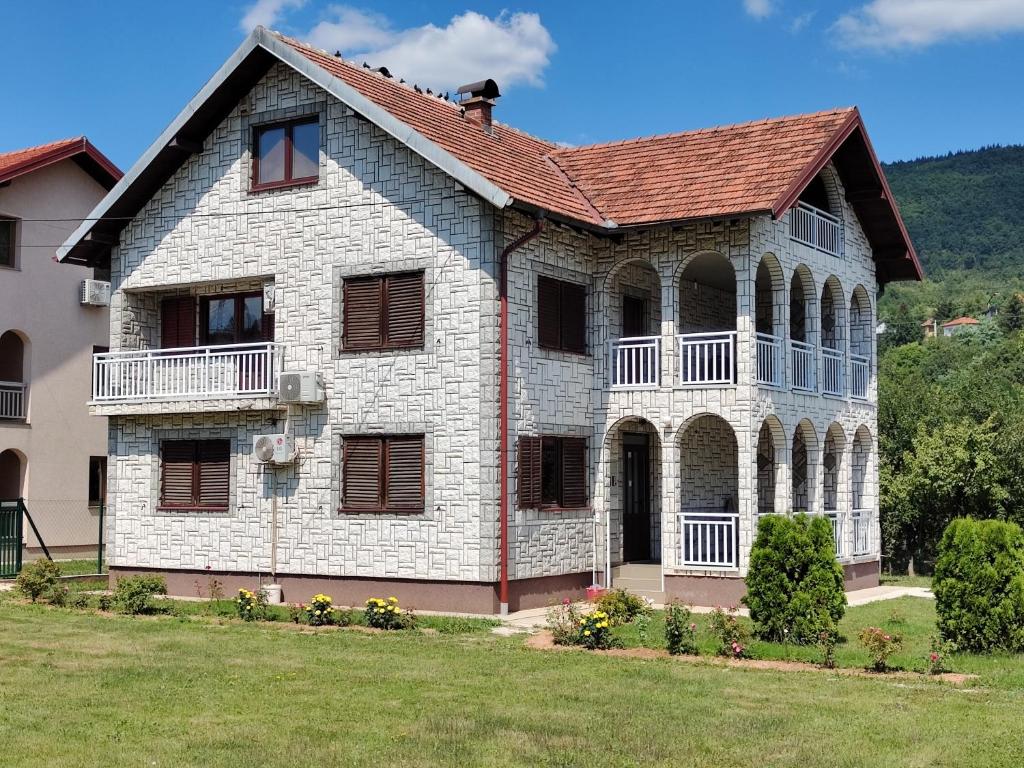 une grande maison en briques blanches avec un toit rouge dans l'établissement Vila FH, à Ilijaš