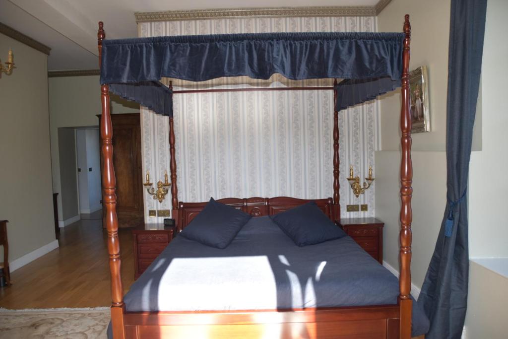 a bedroom with a canopy bed with blue curtains at Chateau Roquehort in Monein