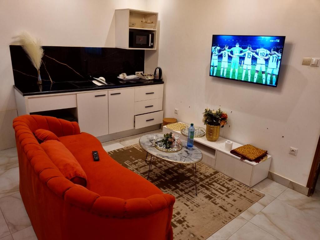 a living room with an orange couch and a tv at Keur Buur in Dakar