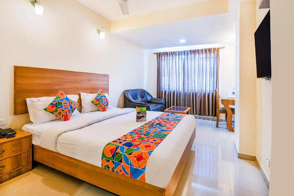 a hotel room with a bed and a chair at FabHotel Jansi Deluxe Gandhipuram in Coimbatore