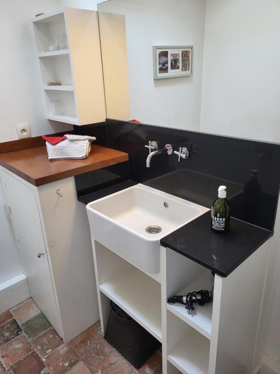 a bathroom with a white sink and a black counter at Ma Chambre d'Amis in Saint-Clément-des-Baleines