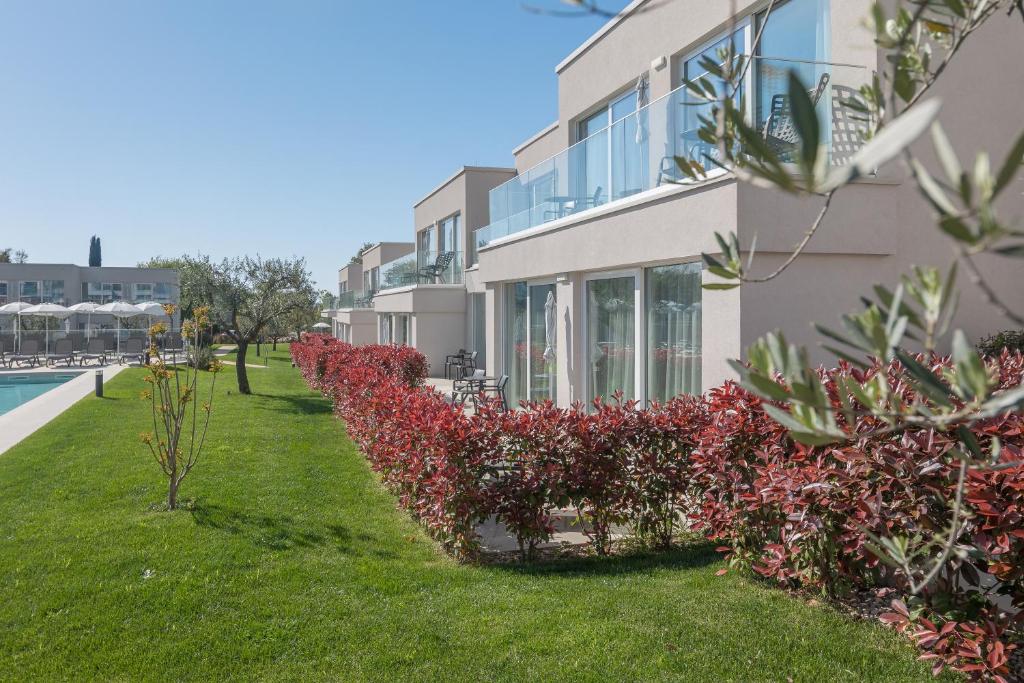 a building with red flowers next to a swimming pool at Maj Luxury Residence in Poreč