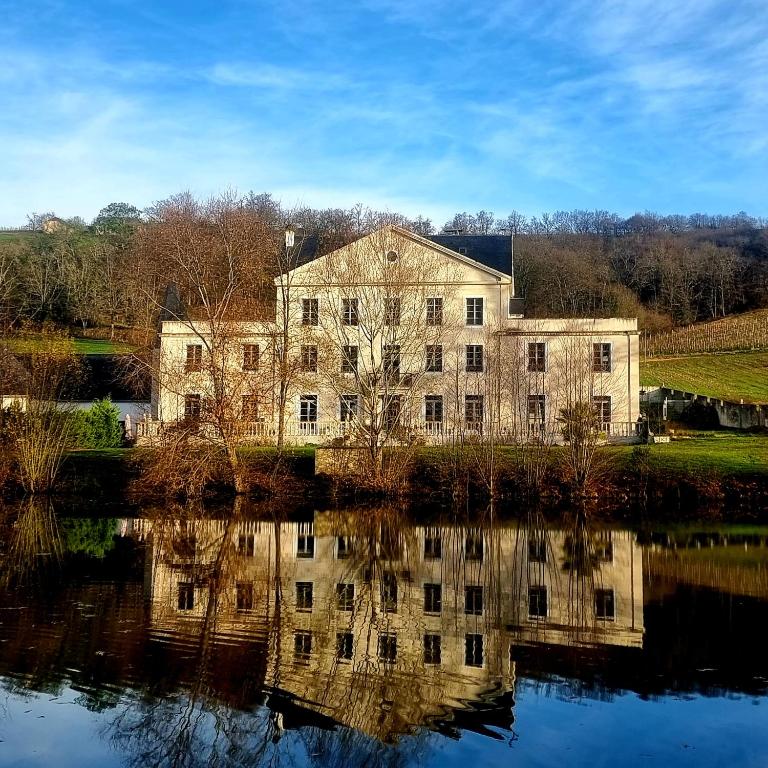 un vieux bâtiment avec sa réflexion dans l'eau dans l'établissement Chateau Roquehort avec EV recharge point 22kw, à Monein