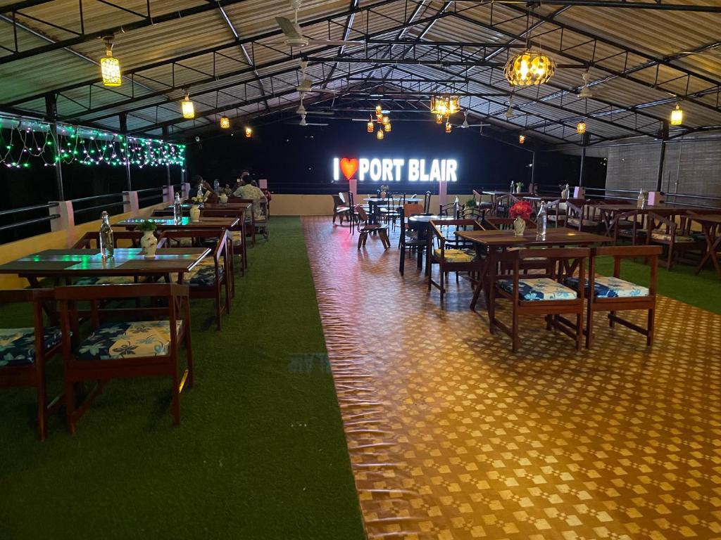 un ristorante con tavoli e sedie in legno e un cartello di Amaravathi hotel and restaurant a Port Blair