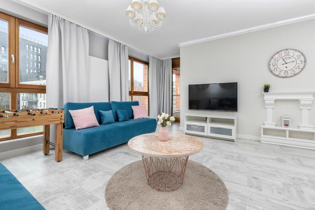 a living room with a blue couch and a table at Modern Apartment in Gdańsk Center Near the River with Parking by Renters in Gdańsk