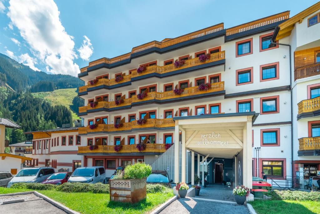 a hotel with cars parked in a parking lot at JUFA Alpenhotel Saalbach in Saalbach Hinterglemm