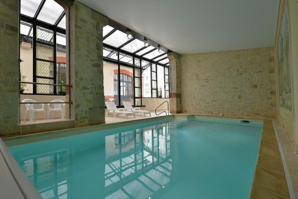 a swimming pool in a building with windows at Hôtel Castel Jeanson in Ay