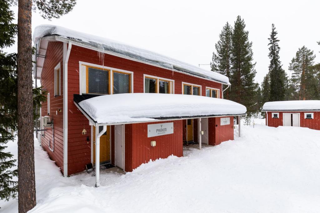 a red cabin with snow on the roof at Pyhäkoti Holiday Home in Pyhätunturi