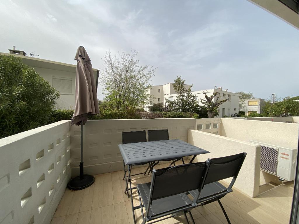 une table et des chaises sur un balcon avec un parasol dans l'établissement Sol-y-Days les Tamaris Grand Studio familial avec terrasse, au Grau-du-Roi