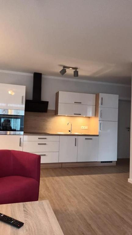 eine Küche mit weißen Schränken und einer roten Couch in der Unterkunft NEU! Ferienwohnung Flut Ostfriesland in Marienhafe