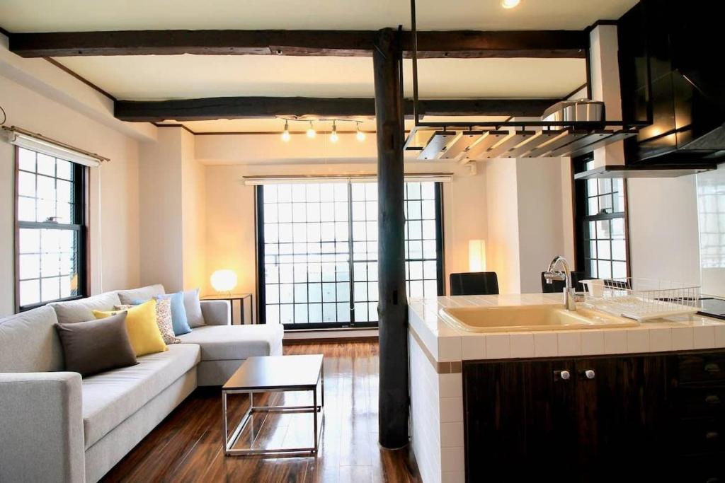 Una cocina y una sala de estar con un sofá y una mesa. en Pacifica by b hotel - 30sec walk to PeacePark, Beautiful Condo, en Hiroshima