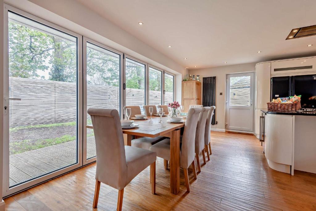 a dining room with a table and chairs at Oakwood Bungalow Christchurch Sleeps 8 in Iford