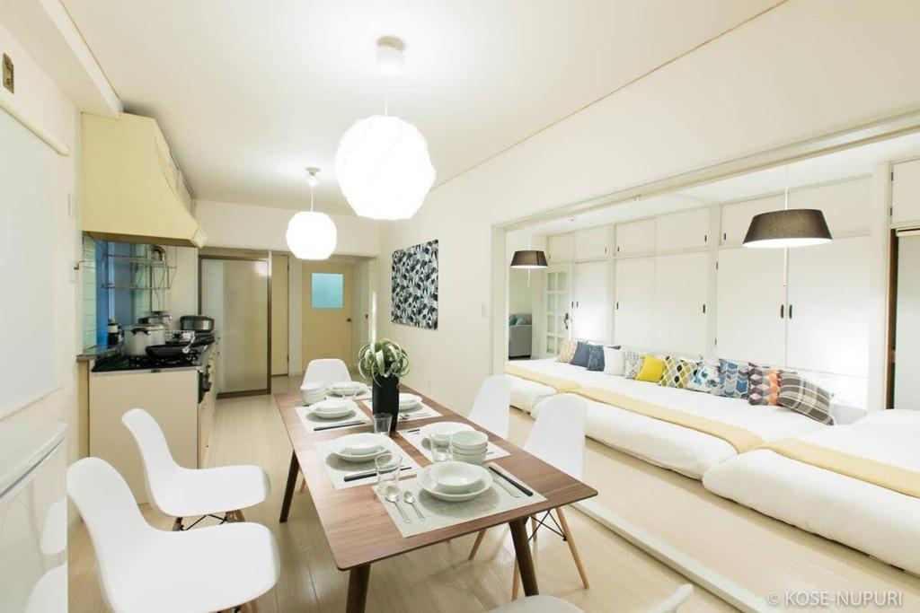 a living room with a couch and a table and chairs at bHOTEL Marumasa - Spacious next to PeacePark Family Condo Up to 13 P in Hiroshima