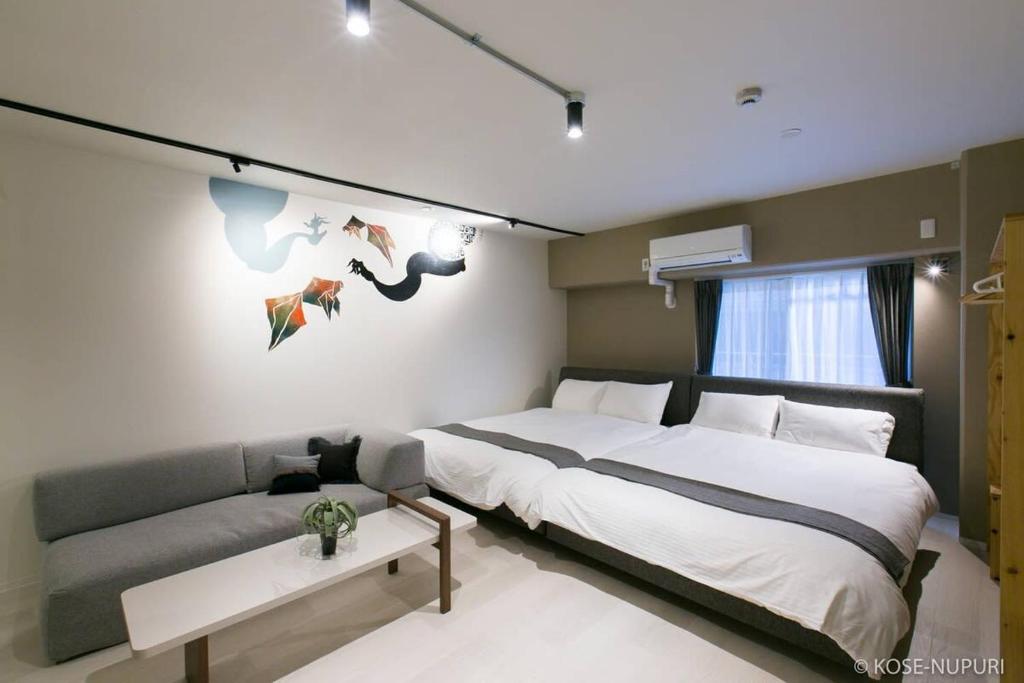 Un dormitorio con una cama grande y un sofá. en Origaminn 302 by b hotel - 5 mins PeacePark, en Hiroshima
