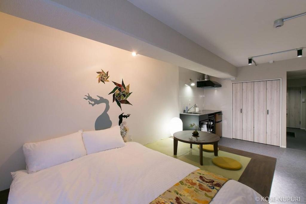 a bedroom with a white bed and a table at bHOTEL Origaminn 303 - 5 mins PeacePark in Hiroshima