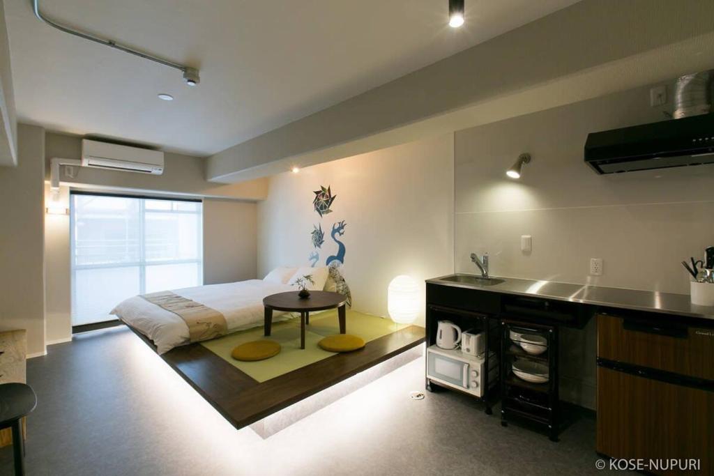 a bedroom with a bed and a kitchen with a sink at Origaminn 403 by b hotel - 5 mins PeacePark in Hiroshima