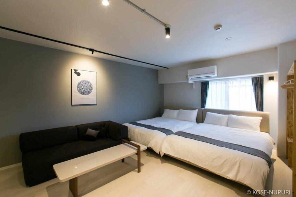 een slaapkamer met een groot bed en een bank bij bHOTEL Origaminn 502 - 5 mins PeacePark in Hiroshima