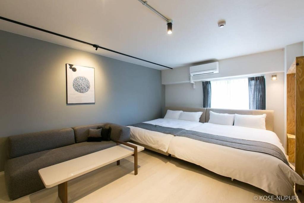 a bedroom with a large bed and a couch at bHOTEL Origaminn 702 - 5 mins PeacePark in Hiroshima