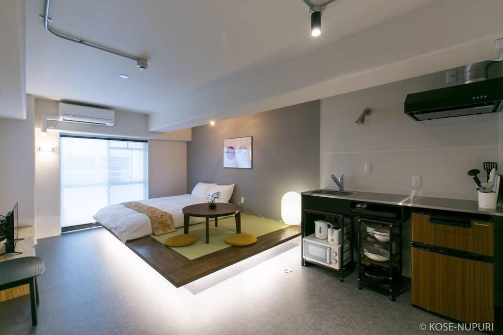 bHOTEL Origaminn 503 - 5 mins PeacePark في هيروشيما: غرفة نوم بسرير ومطبخ مع طاولة