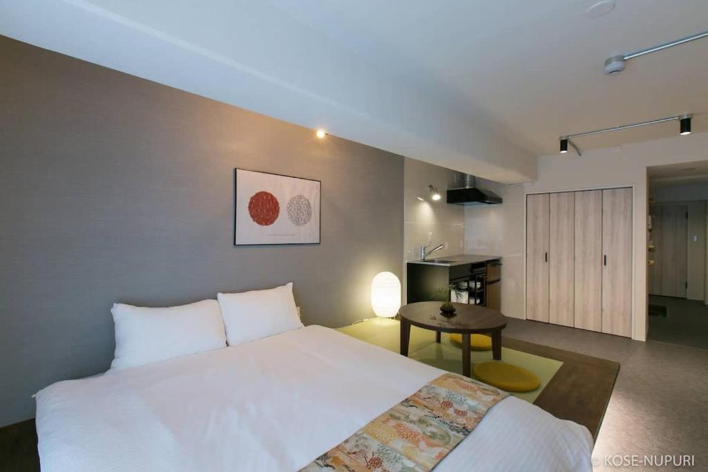 a bedroom with a large white bed and a table at bHOTEL Origaminn 603 - 5 mins PeacePark in Hiroshima