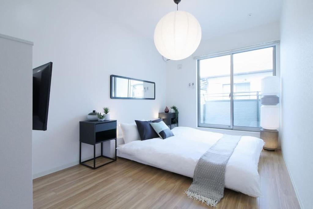 a white bedroom with a large bed and a window at bHOTEL Ball Park - Apt 2mins to Baseball 5mins to Hiroshima Sta 4ppl in Hiroshima