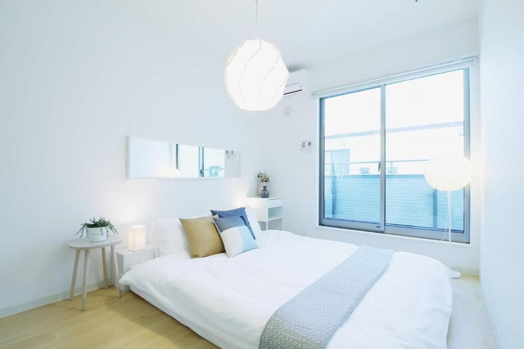 a white bedroom with a bed and a large window at b hotel Ball Park - Apt 2mins to Baseball 5mins to Hiroshima Sta in Hiroshima