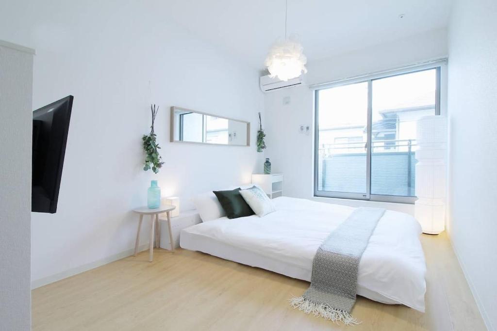 a white bedroom with a bed and a window at bHOTEL Ball Park - 2mins walk Baseball 5mins walk Hiroshima Sta 4ppl in Hiroshima