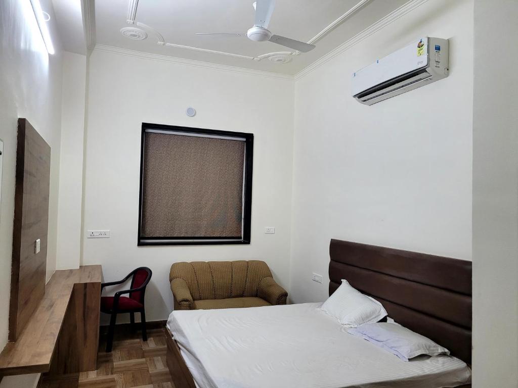 a bedroom with a bed and a chair and a window at Marks Farm in Alwar