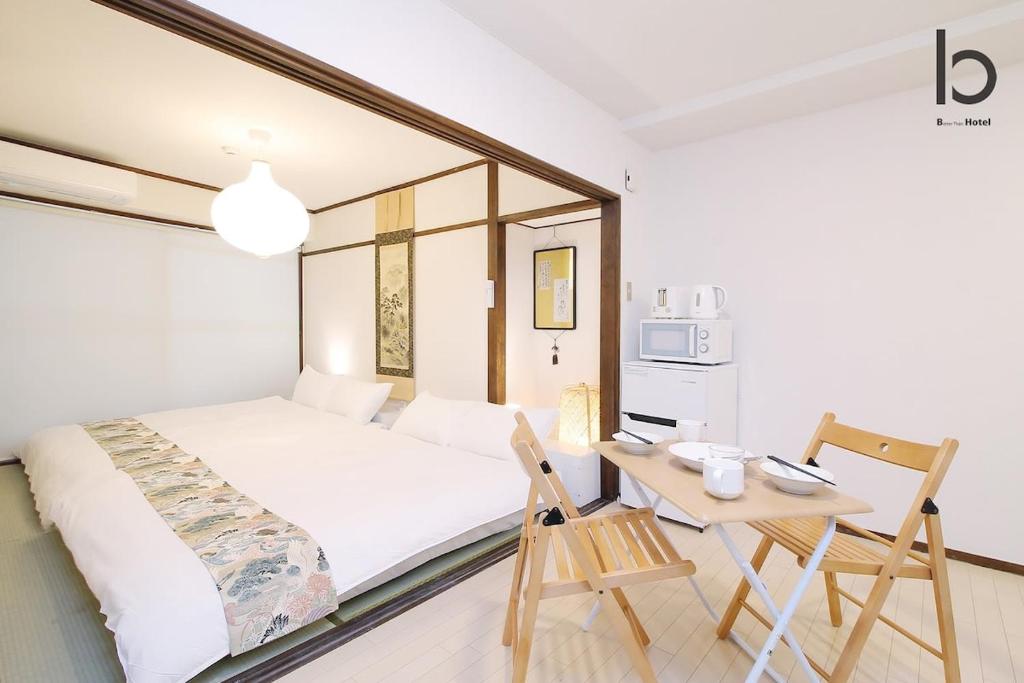 een slaapkamer met een bed en een tafel en stoelen bij Dai3Himawari - Stylish Apt 3mins walk PeacePark 4ppl in Hiroshima