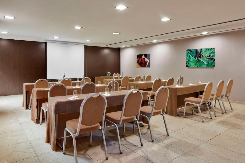 einen Konferenzraum mit Tischen, Stühlen und einem Bildschirm in der Unterkunft NH Tenerife in Santa Cruz de Tenerife